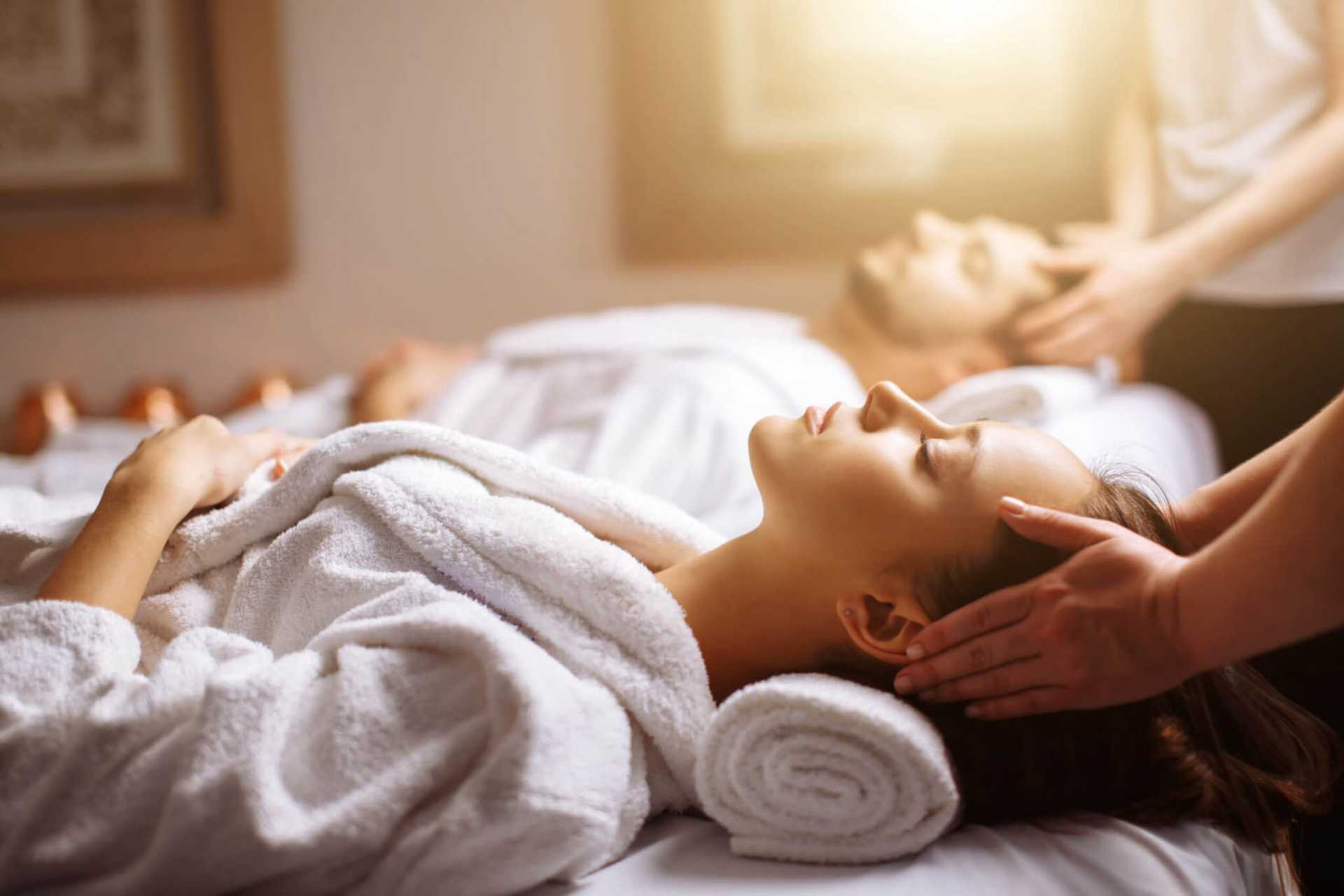 Couple enjoying a relaxing massage at a spa, lying on massage tables in cozy robes.