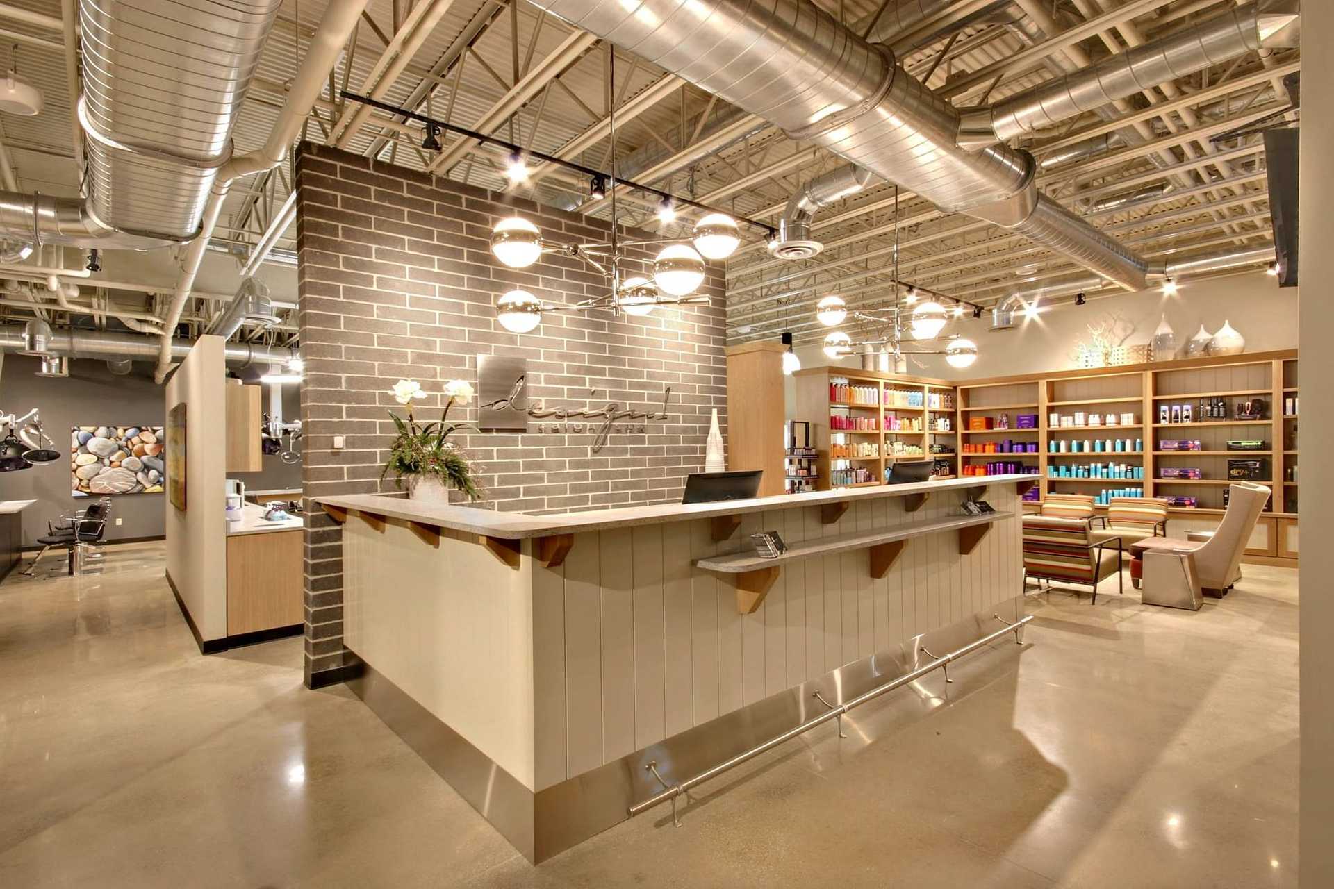 Modern salon reception area with sleek design, industrial ceiling, and colorful shelves.