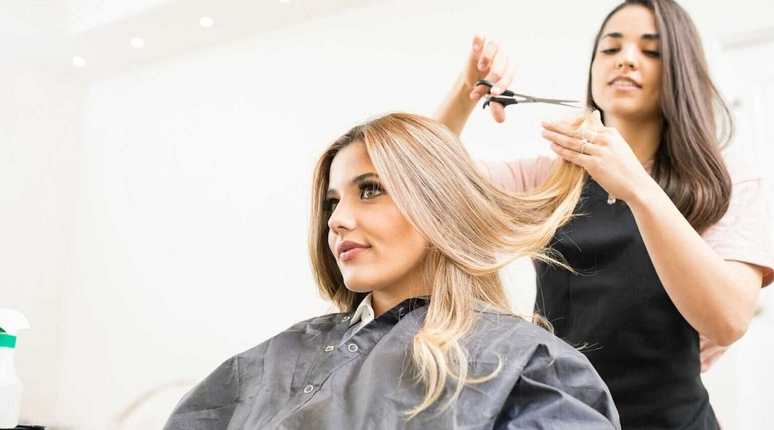 Hair stylist cutting a woman's hair in a salon.