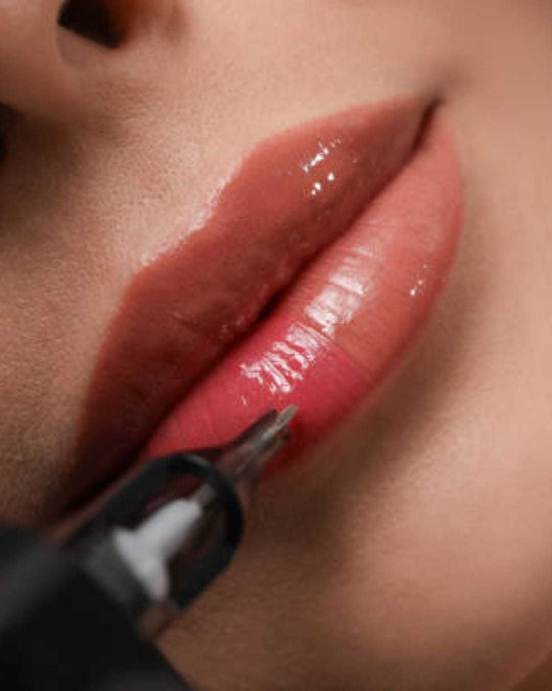 Close-up of glossy lips receiving permanent makeup treatment.