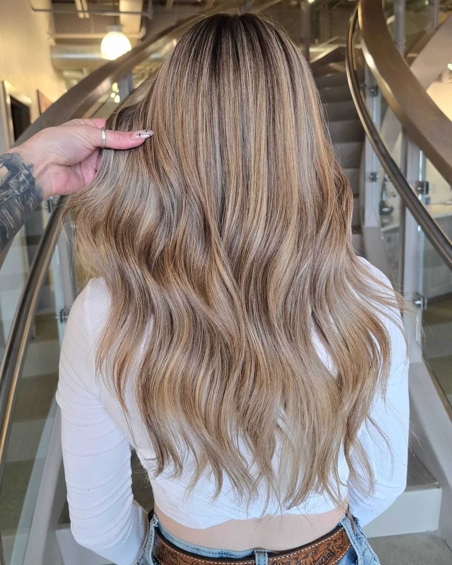 Long wavy blonde hair styled elegantly with soft curls, showcased in a modern setting.