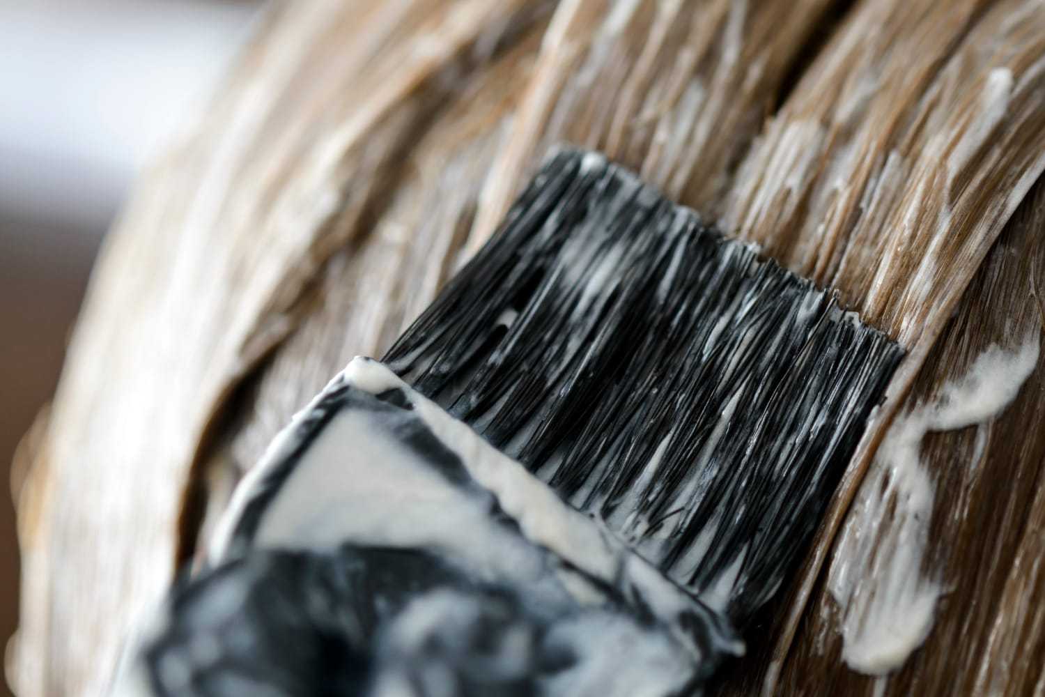 Hair being dyed with a brush, showing close-up of cream being applied.