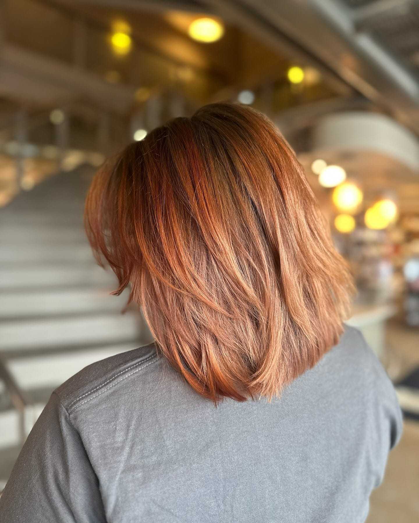 Short-haired person with auburn highlights in bright indoor setting.